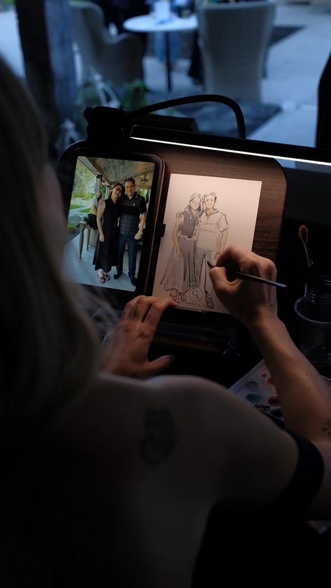 An event artist drawing a guest couple from their reference photo.