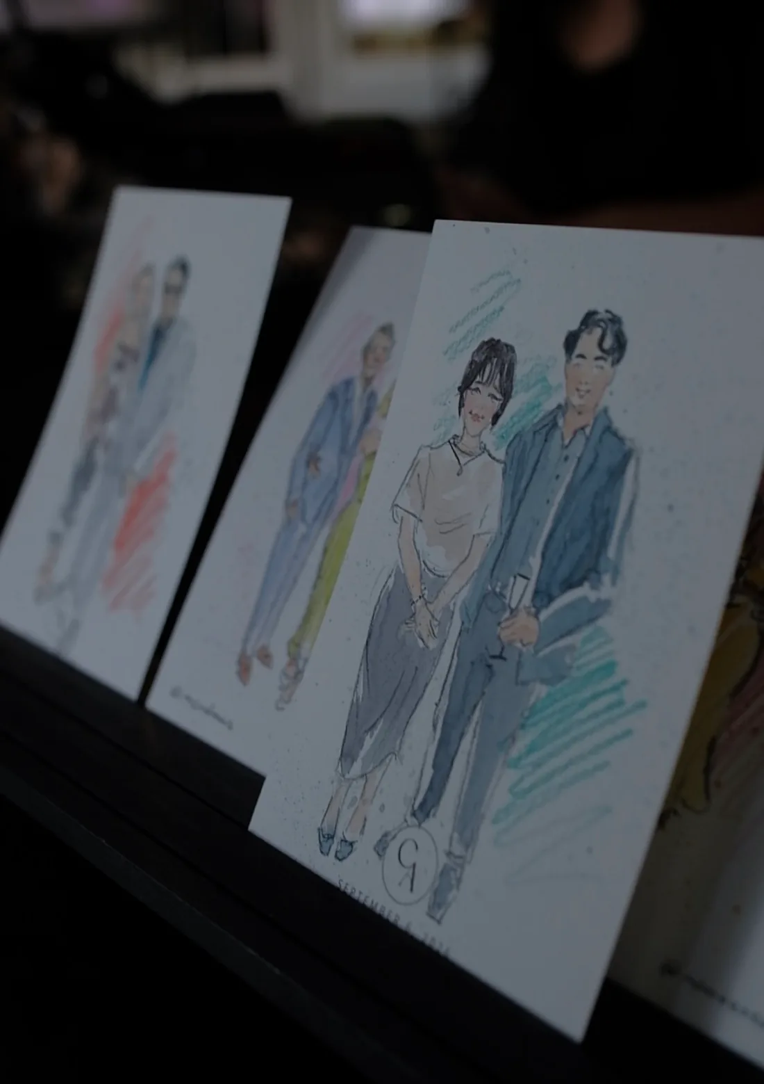 Several finished illustrated portraits of guest couples displayed together.