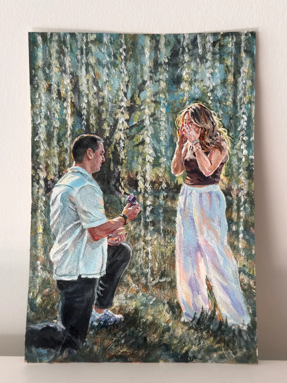Finished acrylic portrait of a marriage proposal beneath flowering trees.