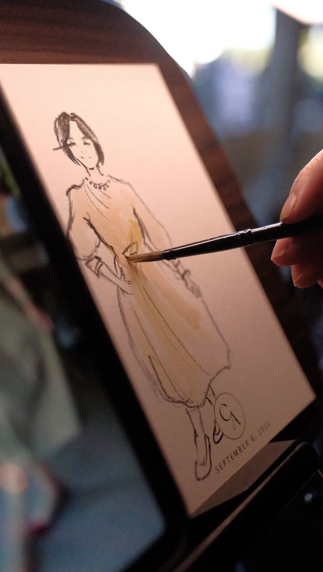 An artist adding colour to a live fashion-style guest sketch.